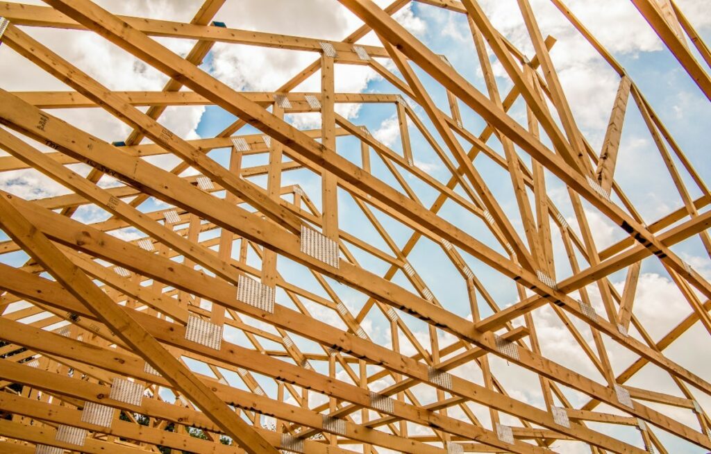 Konstrukcja dachu z drewnianych krokwi w różnych odmianach ułożonych na budowie.