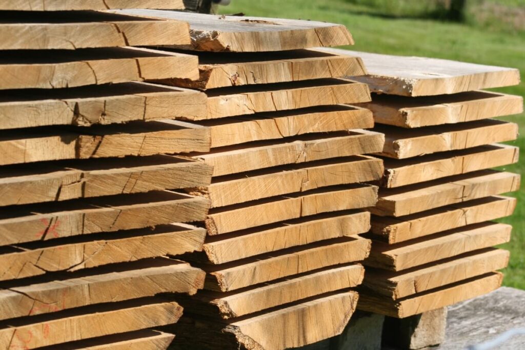 Stos drewnianych desek to tarcica suszona, przygotowana do dalszego użytku.