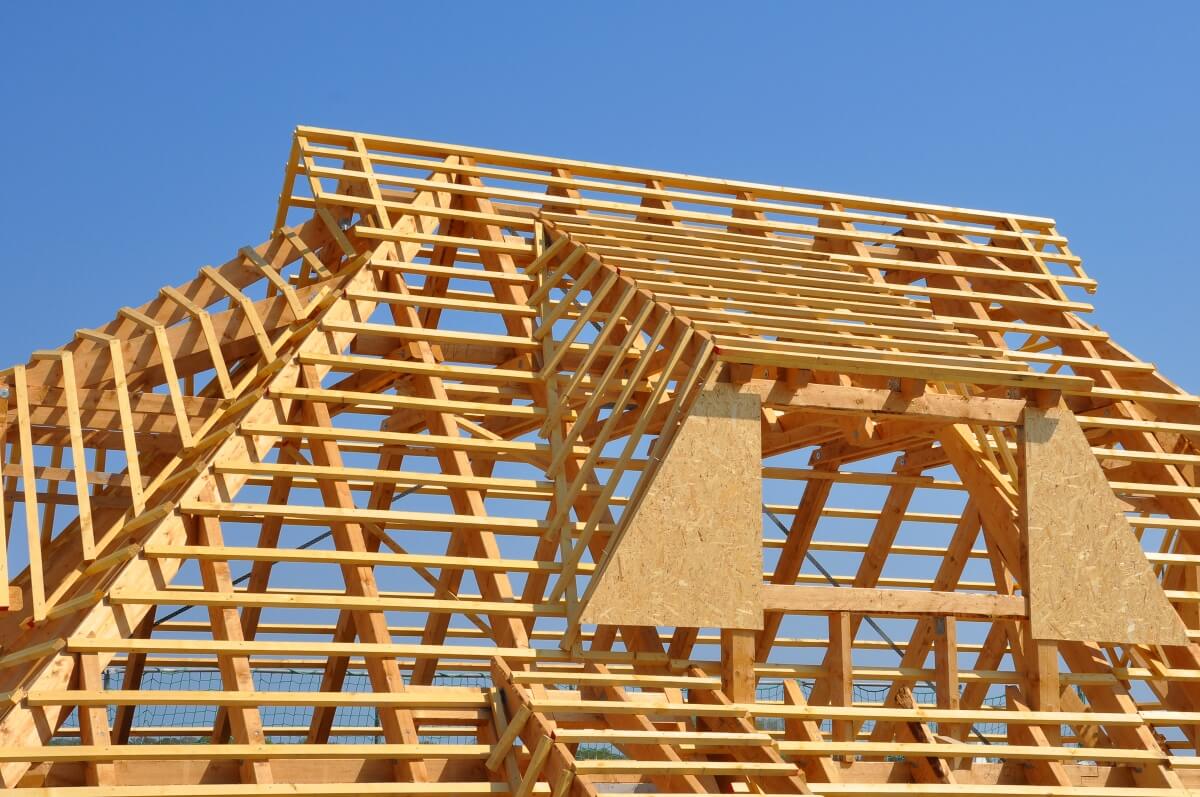 Drewniana więźba dachowa na tle błękitnego nieba.