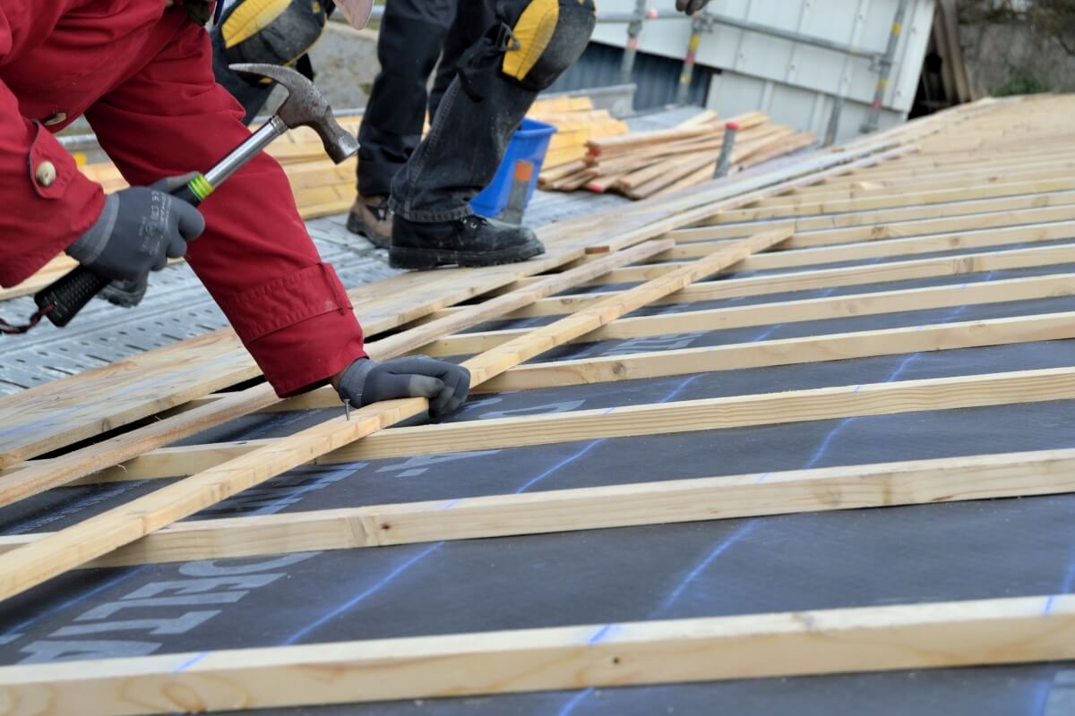 Robotnicy montują łaty i kontrłaty na dachu.