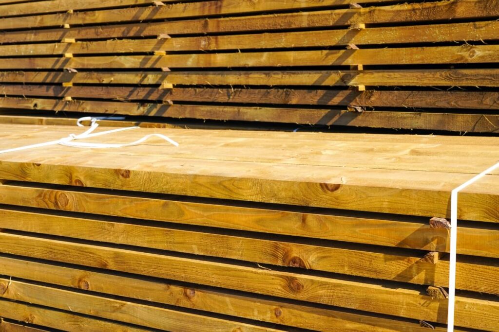 Stosy tarcicy impregnowanej ułożonej na placu składowym.